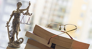 Eine Figur der Justizia auf einem Schreibtisch mit Büchern